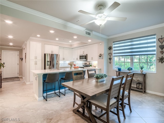 dining room with ceiling fan, light tile patterned flooring, ornamental molding, and sink