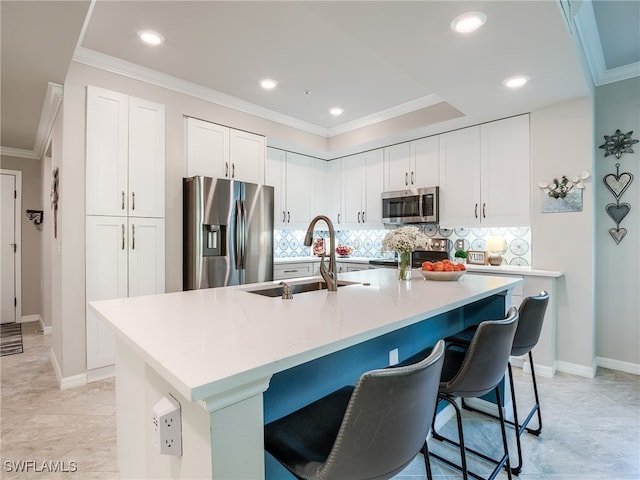 kitchen featuring stainless steel appliances, white cabinetry, a kitchen island with sink, and sink