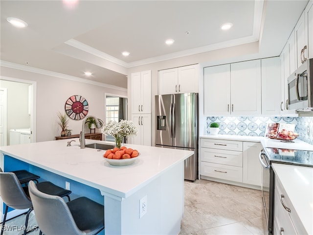 kitchen with sink, an island with sink, tasteful backsplash, white cabinetry, and stainless steel appliances