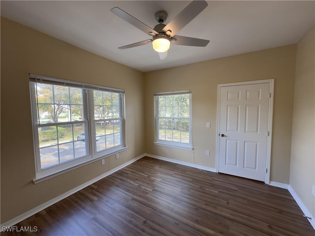 unfurnished room with a healthy amount of sunlight, dark wood-type flooring, and ceiling fan