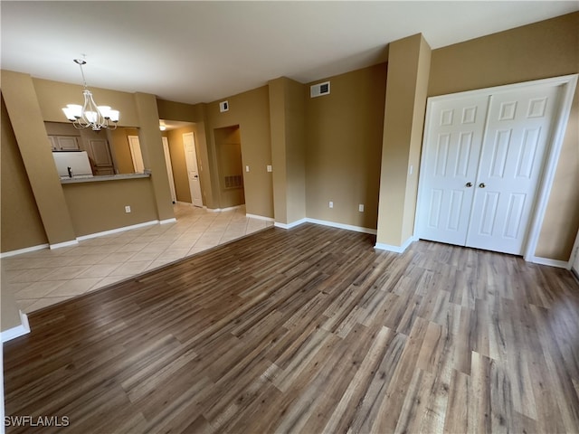 unfurnished living room with light hardwood / wood-style floors and an inviting chandelier