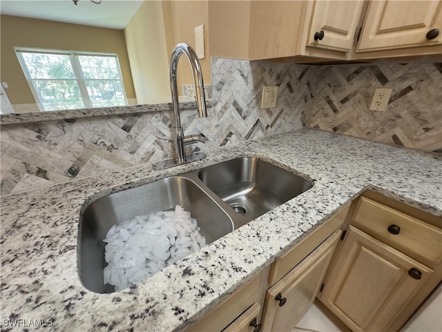 room details with decorative backsplash, sink, and light stone counters