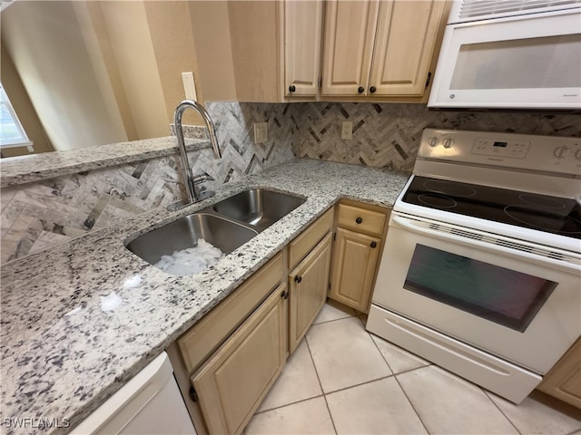 kitchen with light brown cabinets, backsplash, light stone countertops, sink, and white appliances