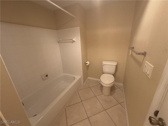 bathroom featuring tiled shower / bath, toilet, and tile patterned flooring