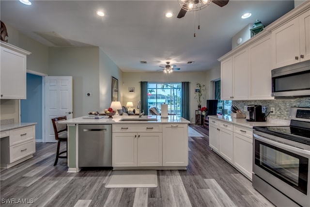 kitchen featuring appliances with stainless steel finishes, sink, a kitchen island with sink, and hardwood / wood-style floors