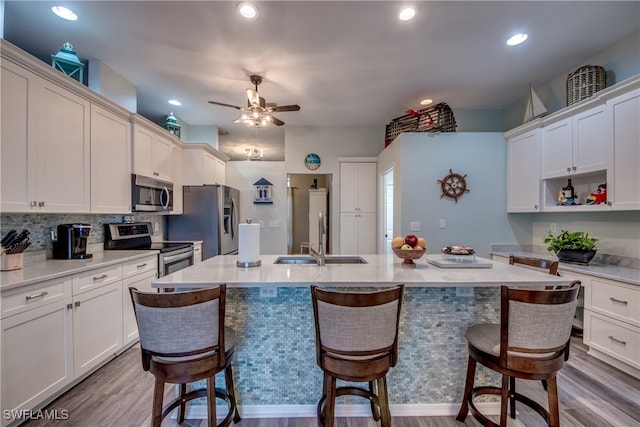 kitchen featuring wood-type flooring, appliances with stainless steel finishes, a kitchen breakfast bar, and sink