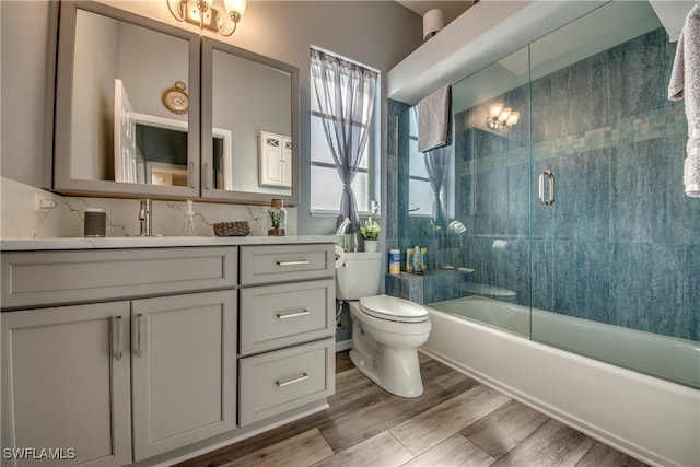 full bathroom with hardwood / wood-style floors, vanity, toilet, and shower / bath combination with glass door