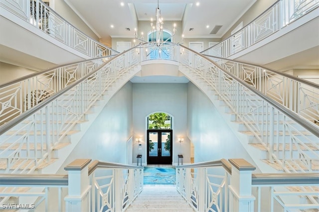 stairs featuring a high ceiling, french doors, ornamental molding, and wood-type flooring