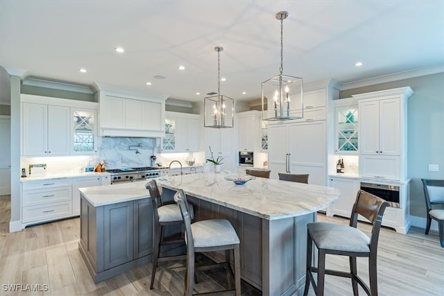 kitchen with a kitchen breakfast bar, a spacious island, light hardwood / wood-style flooring, white cabinetry, and decorative light fixtures