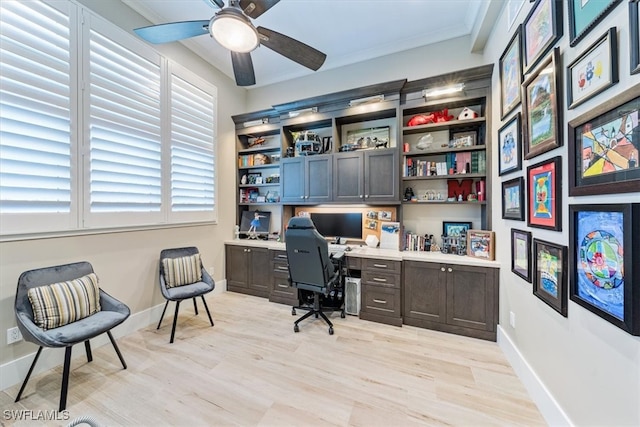 office space featuring crown molding, light hardwood / wood-style floors, built in desk, and ceiling fan