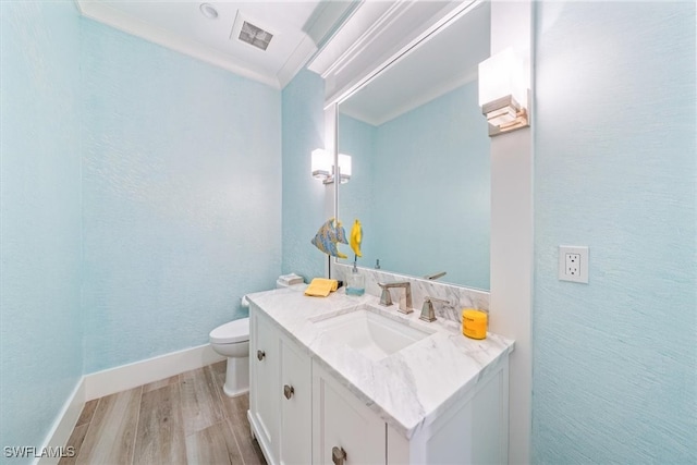 bathroom with ornamental molding, vanity, hardwood / wood-style flooring, and toilet