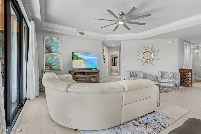 living room with light hardwood / wood-style floors, ornamental molding, a tray ceiling, and ceiling fan