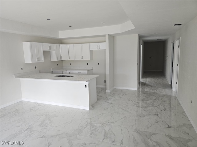 kitchen with sink, kitchen peninsula, and white cabinets