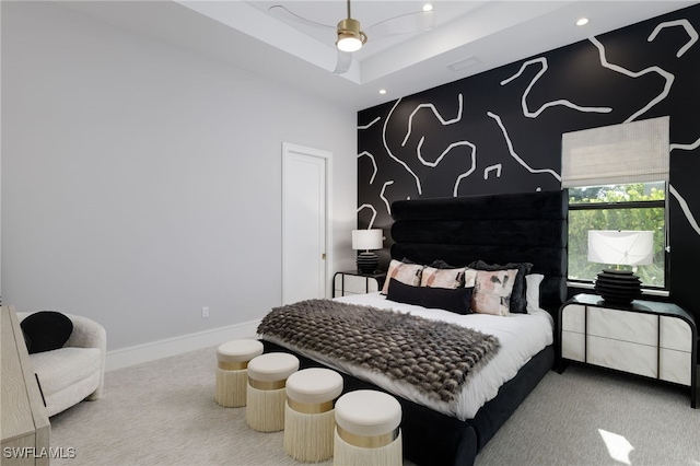 carpeted bedroom with a raised ceiling and ceiling fan