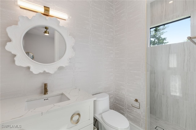 bathroom with toilet, walk in shower, vanity, and tile walls