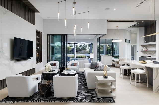 living room with light hardwood / wood-style floors and a towering ceiling