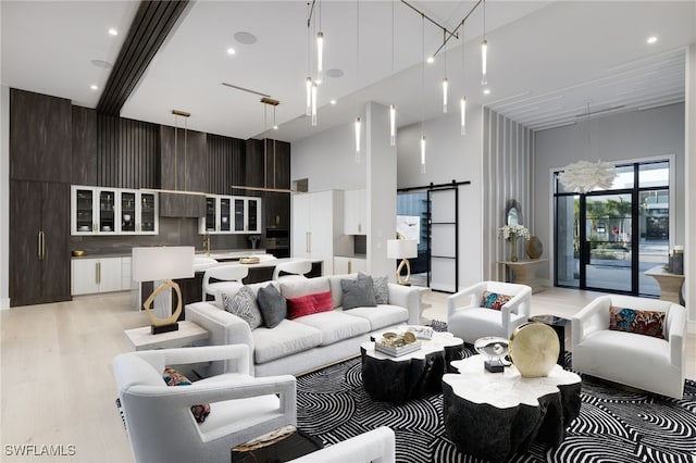 living room with a towering ceiling, light hardwood / wood-style flooring, and a barn door