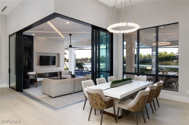 dining space featuring ceiling fan with notable chandelier and light wood-type flooring