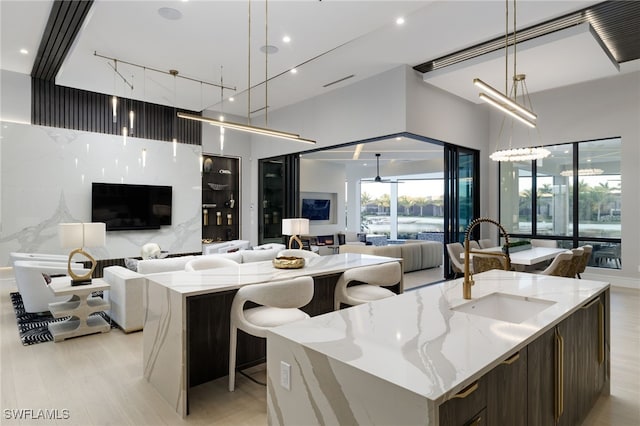 kitchen featuring a large island, light stone countertops, decorative light fixtures, and sink