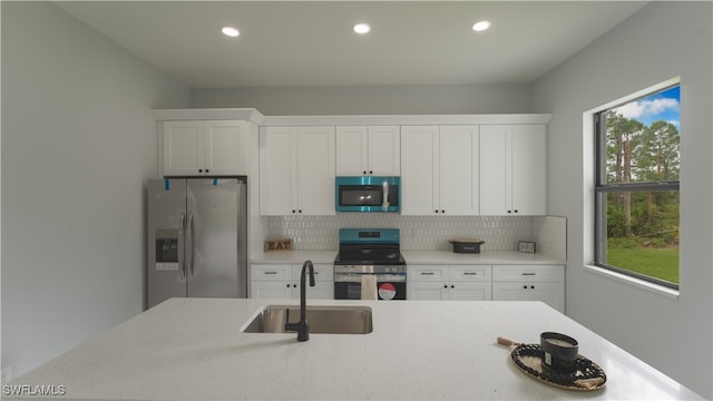 kitchen featuring white cabinetry, stainless steel appliances, sink, and backsplash