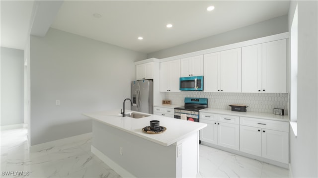 kitchen featuring white cabinets, tasteful backsplash, a center island with sink, sink, and stainless steel appliances