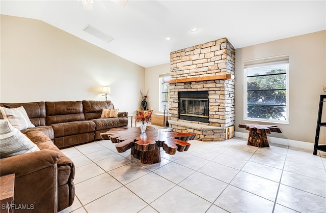 tiled living room with vaulted ceiling and a stone fireplace