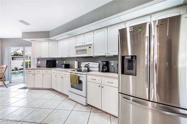 kitchen featuring white cabinetry, light tile patterned flooring, and white appliances