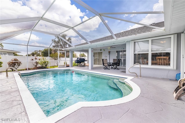 view of swimming pool with a patio area, glass enclosure, and ceiling fan