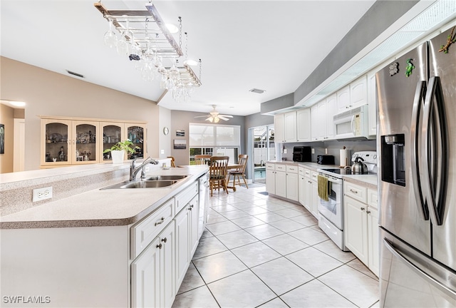 kitchen with white appliances, light tile patterned flooring, sink, white cabinetry, and vaulted ceiling