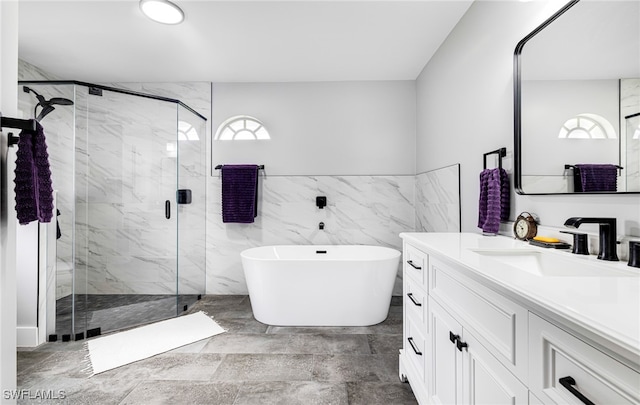 bathroom with tile walls, vanity, shower with separate bathtub, and a healthy amount of sunlight