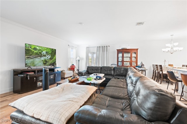 living room with ornamental molding, a chandelier, and light hardwood / wood-style flooring