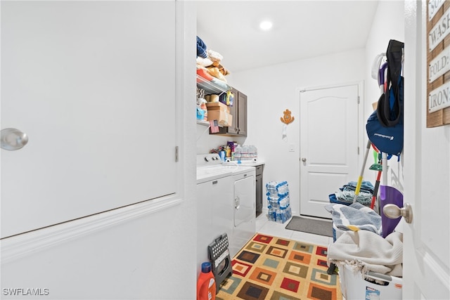 washroom with independent washer and dryer, cabinets, and light tile patterned floors