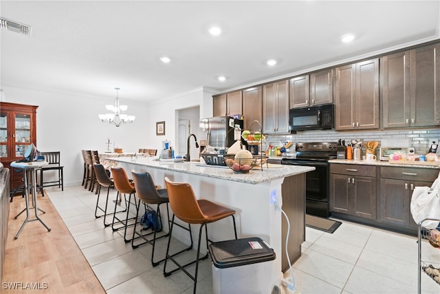 kitchen with appliances with stainless steel finishes, a kitchen island with sink, backsplash, and pendant lighting