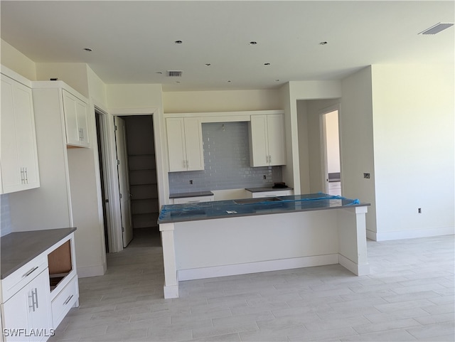 kitchen featuring backsplash, white cabinets, and a kitchen island