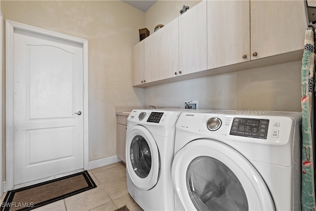 clothes washing area featuring cabinets, light tile patterned flooring, and washing machine and clothes dryer