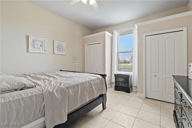 bedroom featuring multiple closets, light tile patterned floors, and ceiling fan