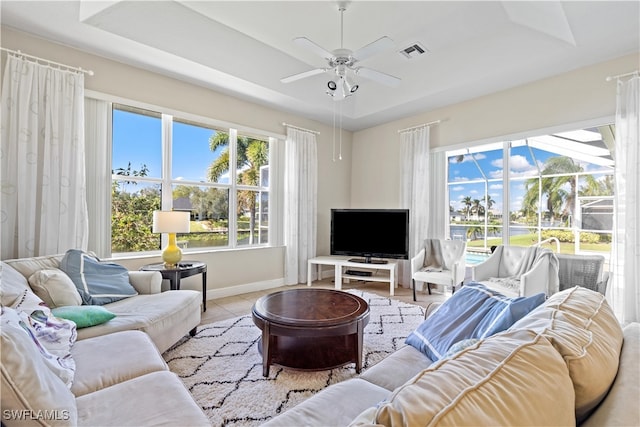 tiled living room featuring a tray ceiling and ceiling fan