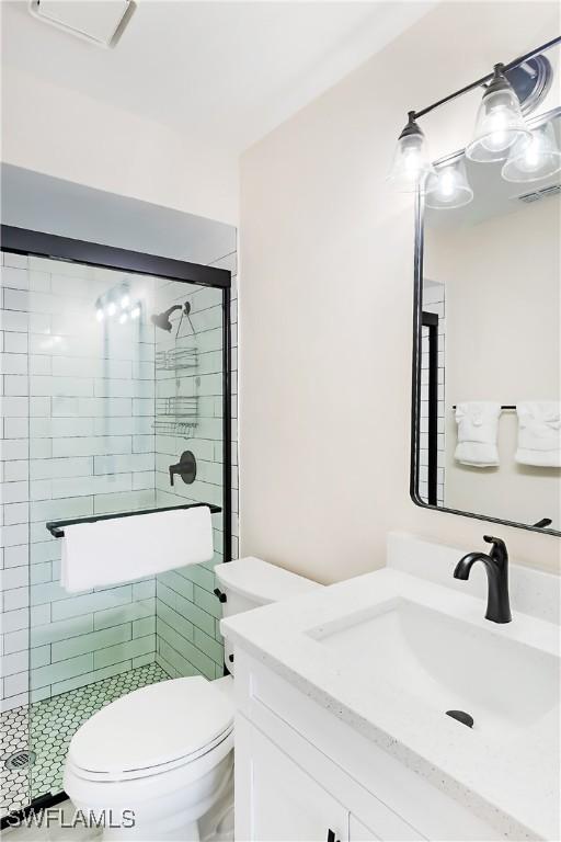 bathroom featuring toilet, vanity, and a stall shower