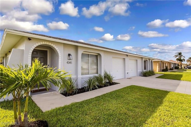 view of front facade with stucco siding, concrete driveway, a front yard, and a garage