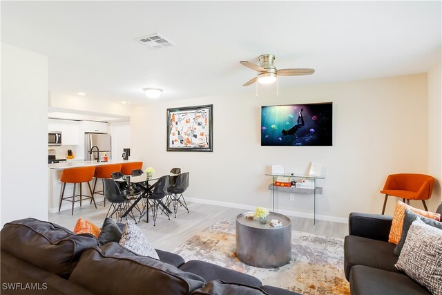 living room featuring ceiling fan and light hardwood / wood-style flooring