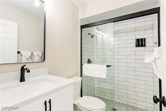 bathroom featuring toilet, vanity, and a shower with door