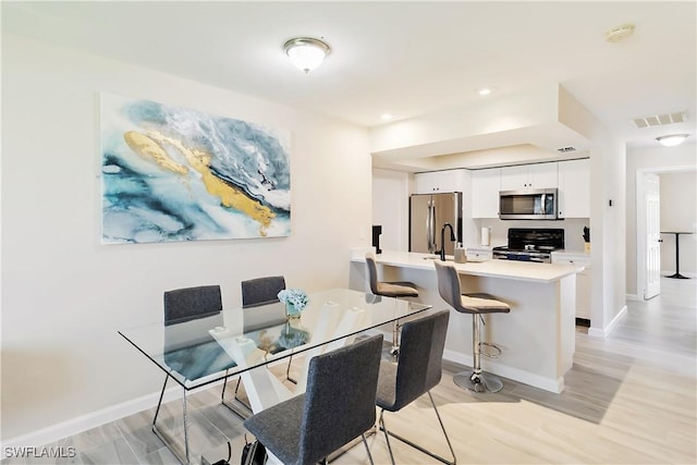 dining space with baseboards and light wood-type flooring