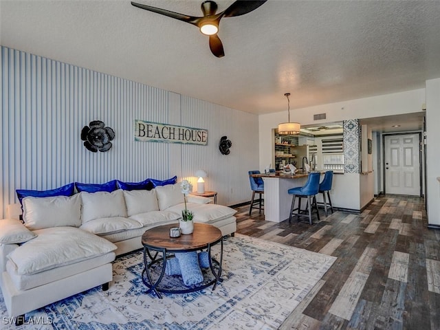 living room with ceiling fan, a textured ceiling, and dark hardwood / wood-style flooring