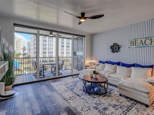 living room with a textured ceiling, hardwood / wood-style flooring, ceiling fan, and a wall of windows