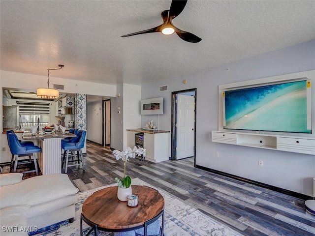 living room with a textured ceiling, hardwood / wood-style flooring, and ceiling fan