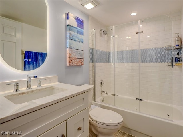 full bathroom featuring toilet, vanity, and shower / bath combination with glass door