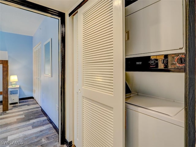 laundry area featuring stacked washing maching and dryer and hardwood / wood-style floors