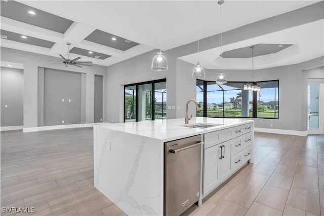 kitchen with white cabinetry, a wealth of natural light, pendant lighting, and a center island with sink