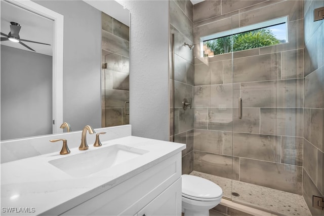 bathroom with vanity, toilet, an enclosed shower, and ceiling fan