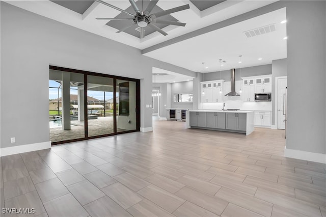 unfurnished living room featuring ceiling fan, a high ceiling, and light wood-type flooring